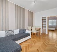 Vkusne zrekonštruovaný 3-izbový byt - Karadžičova ulica, Bratislava - Obývacia izba s oranžovým dreveným nábytkom, pohovkou a jedálenským stolom v 3-izbovom byte.