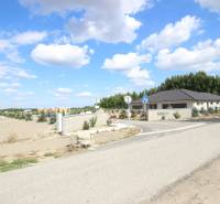 Luxusná veľkometrážna parcela za skvelú cenu Kvetoslavov,2480m2 - Na ulici vidno vstup do oblasti Lesopark, pozemky a bývanie v pozadí.
