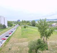 BÝVAJ PRVÝ v 2i byte, DIAMNAT, BALKÓN, KLÍMA, PARKING, Rybničná ulica - Výhľad z Rybničnej ulice v Bratislave - Vajnory s parkoviskom a obytnými budovami.