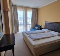 Predaj, 2 i apartmán 72 m2 + balkón výhľad na more, Burgas, BULHARSKO - Spálňa v rekreačnom apartmáne s manželskou posteľou, zrkadlom a výhľadom cez záclony.