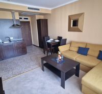 Predaj, 2 i apartmán 72 m2 + balkón výhľad na more, Burgas, BULHARSKO - Interiér rekreačného apartmánu s kuchyňou, sedačkou a jedálenským stolom v teplých farbách.