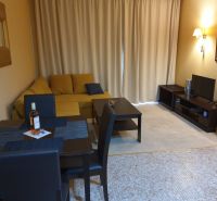 Predaj, 2 i apartmán 72 m2 + balkón výhľad na more, Burgas, BULHARSKO - Obývacia izba Rekreačného apartmánu so žltou sedačkou, jedálenským stolom a televíziou.