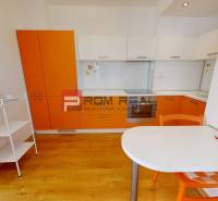 Na PREDAJ 3 izbový  byt priamo v centre mesta Pezinok - Kuchyňa v 3-izbovom byte s oranžovou linkou a nástennými hodinami.