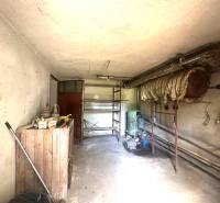 Na predaj Rodinný dom Drietoma – pozemok 745 m2  - Úložný priestor v rodinnom dome s regálmi a starým bojlerom.