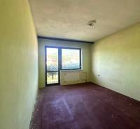 Na predaj Rodinný dom Drietoma – pozemok 745 m2  - Nevybavená izba s výhľadom von, svetlé steny, červená podlaha, okno a dvere.
