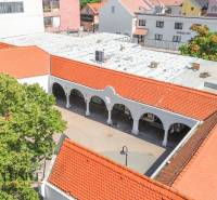 NA PRENÁJOM OBCHODNÝ PRIESTOR V CENTRE,DUNAJSKÁ STREDA - Obchodné priestory v Dunajskej Strede s oblúkmi a červenými strechami pri zástavbe.