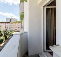 Krásna, dizajnová garsónka 21m2, s balkónom, pri jazere Štrkovec - Balkón v garzónke na Ondavskej ulici, Bratislava - Ružinov, s výhľadom na zeleň a budovy.