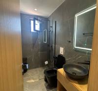 Ksamil – luxusné zariadené apartmány v Maledivách Európy - Kúpeľňa Rekreačného apartmánu so sprchovým kútom, čiernym umývadlom a osvetleným zrkadlom.
