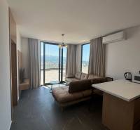 Ksamil – luxusné zariadené apartmány v Maledivách Európy - Obývacia izba v rekreačnom apartmáne s veľkými oknami, pohovkou a kuchynským kútom.