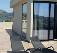 Ksamil – luxusné zariadené apartmány v Maledivách Európy - Terasa rekreačného apartmánu v Ksamil s výhľadom na hory a dve lehátka.