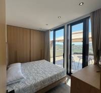 Ksamil – luxusné zariadené apartmány v Maledivách Európy - Spálňa v rekreačnom apartmáne s výhľadom z balkóna, drevený nábytok a posteľ.