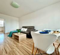 - EXKLUZÍVNE - PREDAJ - 3,5 IZBOVÝ BYT - LEVICE - Obývacia izba v 4-izbovom byte s pohovkou a jedálenským stolom so stoličkami.