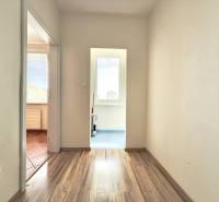 - EXKLUZÍVNE - PREDAJ - 3,5 IZBOVÝ BYT - LEVICE - Chodba 4-izbového bytu s drevenými podlahami a bielymi stenami.