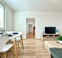 - EXKLUZÍVNE - PREDAJ - 3,5 IZBOVÝ BYT - LEVICE - Obývacia izba v 4-izbovom byte s jedálnym stolom, televízorom a drevenou podlahou.