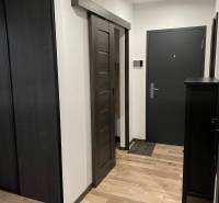 Na predaj krásny komplet prerobený, moderne zariadený 3-izb. byt v BnB - Vstupná chodba do 3-izbového bytu s drevenými podlahami a tmavými posuvnými dverami.