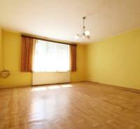 Rodinný dom na rekonštrukciu_Lúky - Izba v Rodinnom dome so žltými stenami, drevenou podlahou a centrálnym lustrom.