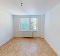 PRENÁJOM - Priestranný moderný 2 izbový byt s 2 balkónmi - Izba s parketami vo svetlom 2-izbovom byte, okno s výhľadom na stromy.