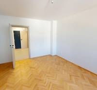 PRENÁJOM - Priestranný moderný 2 izbový byt s 2 balkónmi - Izba v 2-izbovom byte s parketovou podlahou a bielymi stenami.