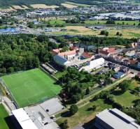 SLOVREAL predaj pozemku Žiar nad Hronom - Letecký pohľad na Žiar nad Hronom, obklopený zeleňou, s futbalovým ihriskom neďaleko centra. Pozemky - bývanie.