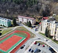 Na predaj 3 izbový byt v meste Kremnica, 78 m2 - Letecký pohľad na sídlisko so športoviskom a 3-izbovými bytmi, obklopené prírodou.