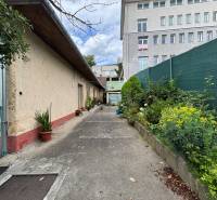 Na predaj starší rodinný dom v centre Ilavy – pozemok 280 m² - Exteriér rodinného domu v Ilave s uličkou a výhľadom na vyššiu budovu.
