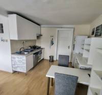 Prenájom pekný 2 izbový, Špitálska ulica, Bratislava I. Staré Mesto - Kuchyňa v 2-izbovom byte s jedálenským stolom, bielymi skrinkami a drevenou podlahou.