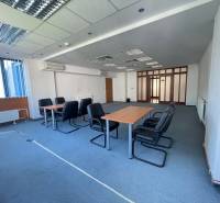 Zrekonštruované Kancelárie v centre mesta - na prízemí, aj na poschodí - Kancelárie s konferenčným stolom, stoličkami a veľkým oknom, podlaha pokrytá kobercom.