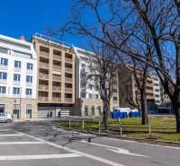 Vynikajúci dizajnový 1,5i byt 30m2 lodžia s výhľadom na Dunaj, VYDRICA - Budovy so stromami na ulici Floriánska, blízko miesta 2-izbový byt, slnečný deň.