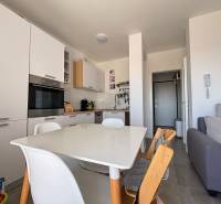 ☀NOVALJA (HR) - apartmán s pekným výhľadom na more  - Kuchyňa v 2-izbovom byte s bielymi spotrebičmi a dreveným jedálenským stolom.