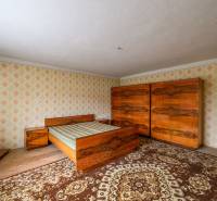 Rodinný dom s veľkým pozemkom na predaj – Vidiná, okres Lučenec - Spálňa v Rodinnom dome s dreveným nábytkom a retro vzormi na stenách.