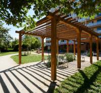 NOVOREKONŠTRUOVANÝ 2 - IZBOVÝ BYT , UL. LOMONOSOVOVA, TERASA - Drevená pergola s lavičkami v parku v Košiciach, mestská časť Juh, obklopená zeleňou.