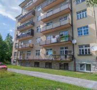 Priestranný 3 a pol izbový byt v Novom Smokovci - Päťposchodová bytovka vo Vysokých Tatrách s balkónmi a zeleným trávnikom.