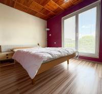 Na prenájom, 5-izbový rodinný dom s pozemkom 2225 m2, Papradno - Svetlá spálňa v rodinnom dome s dreveným stropom a veľkým oknom.