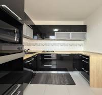 Priestranný 3-izbový byt s balkónom 68 m² Belinského - Kuchyňa v 3-izbovom byte s čiernymi skrinkami a drevenou pracovnou doskou.