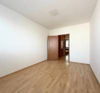 Priestranný 3-izbový byt s balkónom 68 m² Belinského - Prázdna izba s drevenou podlahou a zatvorenými dverami v 3-izbovom byte.