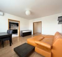 Priestranný 3-izbový byt s balkónom 68 m² Belinského - Obývacia izba v 3-izbovom byte s oranžovou sedačkou a jedálenským stolom.