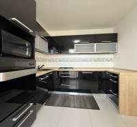 Priestranný 3-izbový byt s balkónom 68 m² Belinského - Čierna kuchyňa so zabudovanými spotrebičmi a drevenou pracovnou doskou v 3-izbovom byte.
