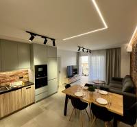 Sarandë - zariadený apartmán, výhľad na more, garážové státie - Obývačka s kuchyňou v Rekreačnom apartmáne. Tehlová stena, jedálenský stôl a pohodlná sedačka.