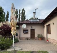 Priestranný rodinný dom v Malackách + pozemok na výstavbu RD v cene - Rodinný dom v Malackách, predný dvor s terasou, zeleňou a satelitnou anténou.