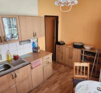 REZERVOVANÝ- 1-izbový byt, Košice, Ružová ulica - Kuchyňa v 1-izbovom byte s drevenými skrinkami, stolom a chladničkou.