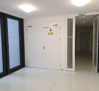Nový moderný byt s balkónom a parkovaním v širšom centre. Jarabinková - Biela chodba s dverami, oknami a označením bezpečnostných pokynov v 2-izbovom byte.