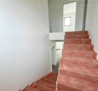 Vám ponúka luxusný rodinný dom v prémiovej loka - V rodinnom dome sú betónové schody a biele steny smerujúce do horného poschodia.