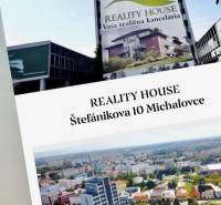 Murovaná Novostavba - Rodinný dom s pekný pozemkom 800 m2 - Pohľad na budovu reality house, kanceláriu Michalovce, rodinné domy v pozadí.