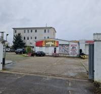 PRENÁJOM: HALA,OBCHODNÝ PRIESTOR 408 m2 v uzatvorenom areáli  - Budova Convoy Truck Shop na ulici Šamorínska, obklopená zaparkovanými autami pri sklade a halách.