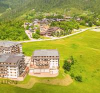 PRIESTRANNÝ 3 IZBOVÝ BYT S TERASOU | DONOVALY  - Letecký pohľad na apartmány blízko ulice Panorama v Donovaloch, obklopené zeleňou a horami.