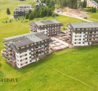 PRIESTRANNÝ 3 IZBOVÝ BYT S TERASOU | DONOVALY  - Pohľad na apartmánové budovy na ulici Panorama v Donovaloch obklopené zelenou krajinou.