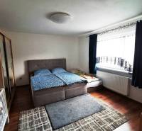 Rodinný dom na predaj Sučany, úplne prerobený ako novostavba - Spálňa v rodinnom dome s posteľou, skrinkou, kobercami a oknom s tmavým závesom.