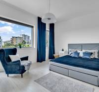 Predaj, Luxusný 4 izbový byt, 180 m2 + 25 m2, Condominium Renaissance - Svetlá spálňa v 4-izbovom byte s veľkým oknom, modrými závesmi a pohodlným kreslom.