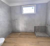 ‼️ NOVO POSTAVENÝ RODINNÝ DOM  S GARÁŽOU NA PREDAJ, MALÉ KRŠTEŇANY  ‼️ - Kúpeľňa v rodinnom dome s dlažbou, pripravená na inštaláciu, svetlo cez malé okno.