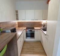 Jedinečný 3-izbový apartmán s balkónom, 71 m², Nový Ružinov - Kuchyňa v 3-izbovom byte so svetlým nábytkom a drevenou pracovnou doskou.
